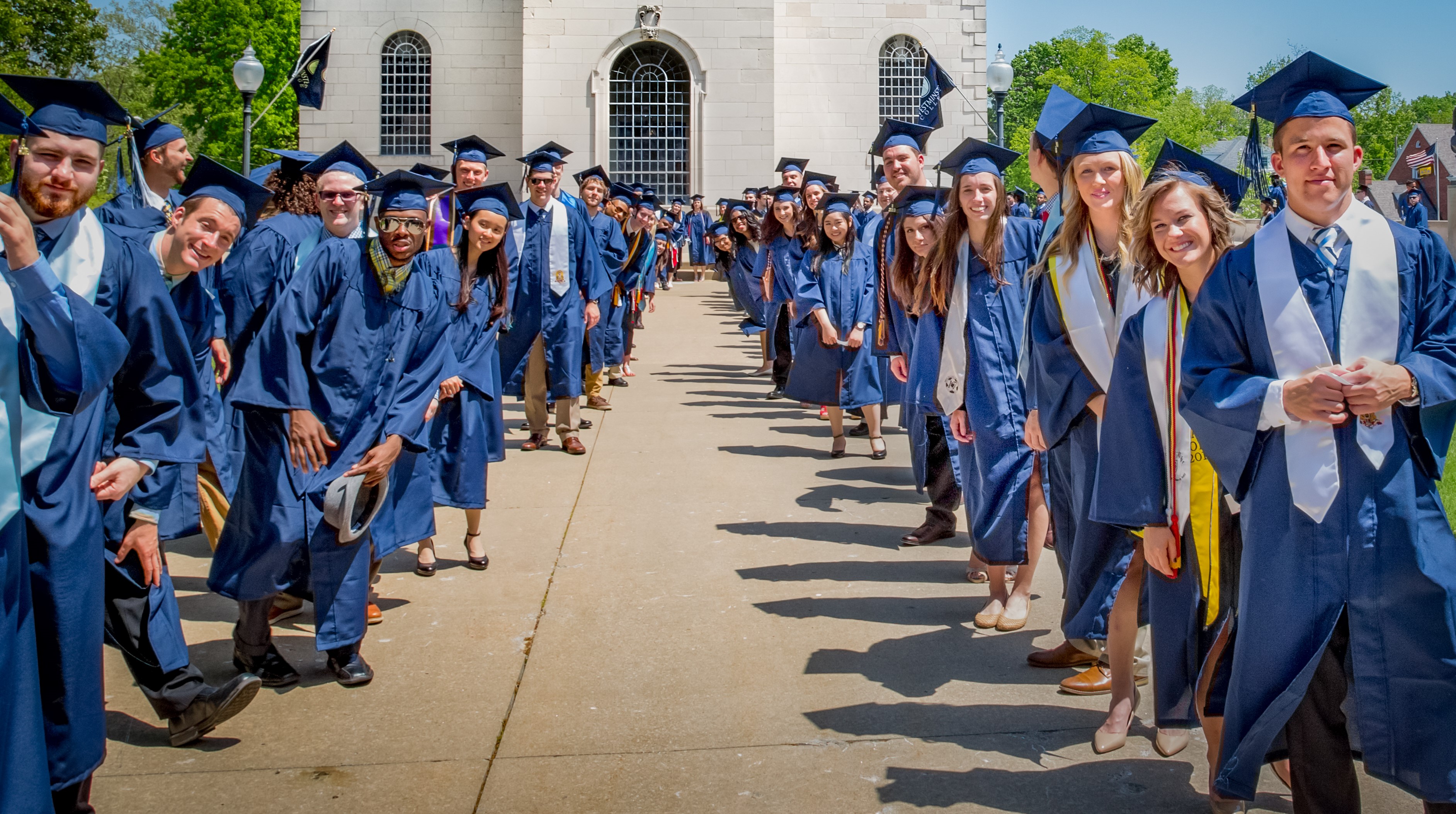 Westminster College Students walking in front of the National Churchill Museum in a Blue graduation cap and gown