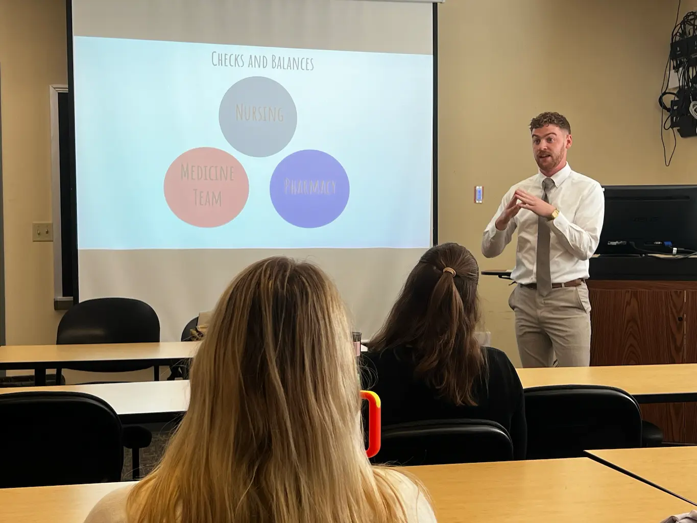 person in a white shirt and tie giving a presentation